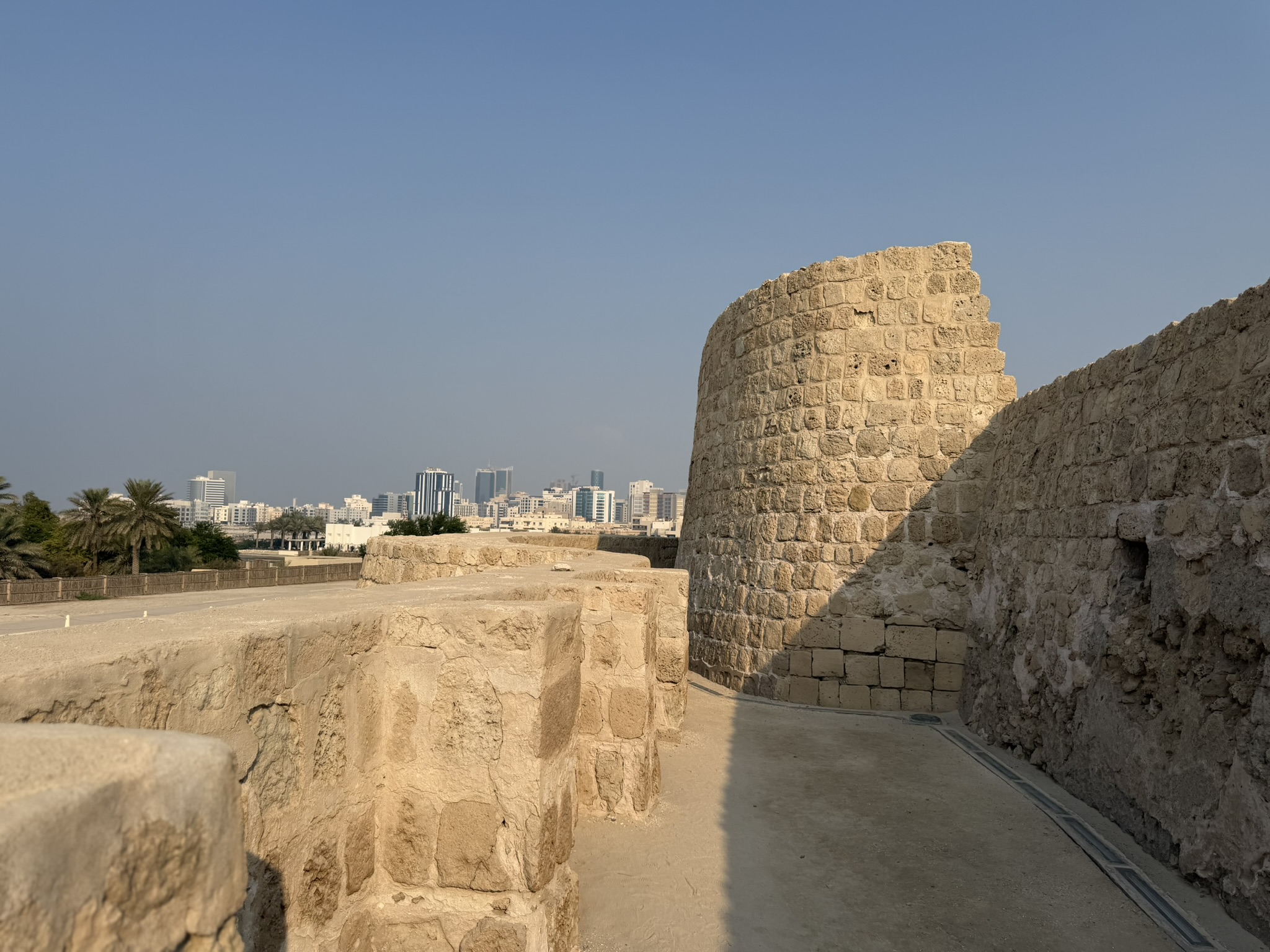 Ancient stone walls of Bahrain Fort with the city skyline in the distance