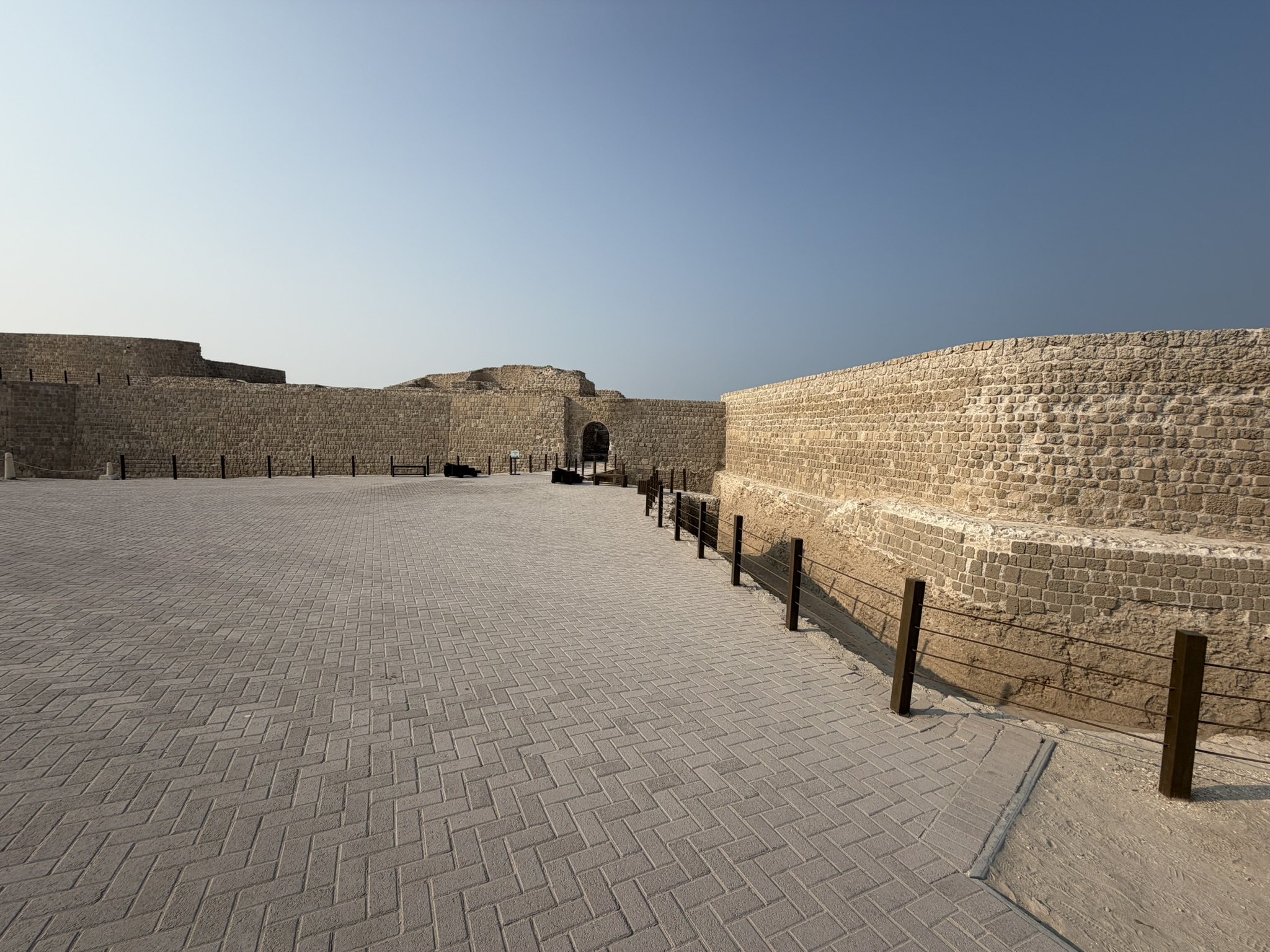The wide stone ramparts and courtyard of Bahrain Fort under a clear sky