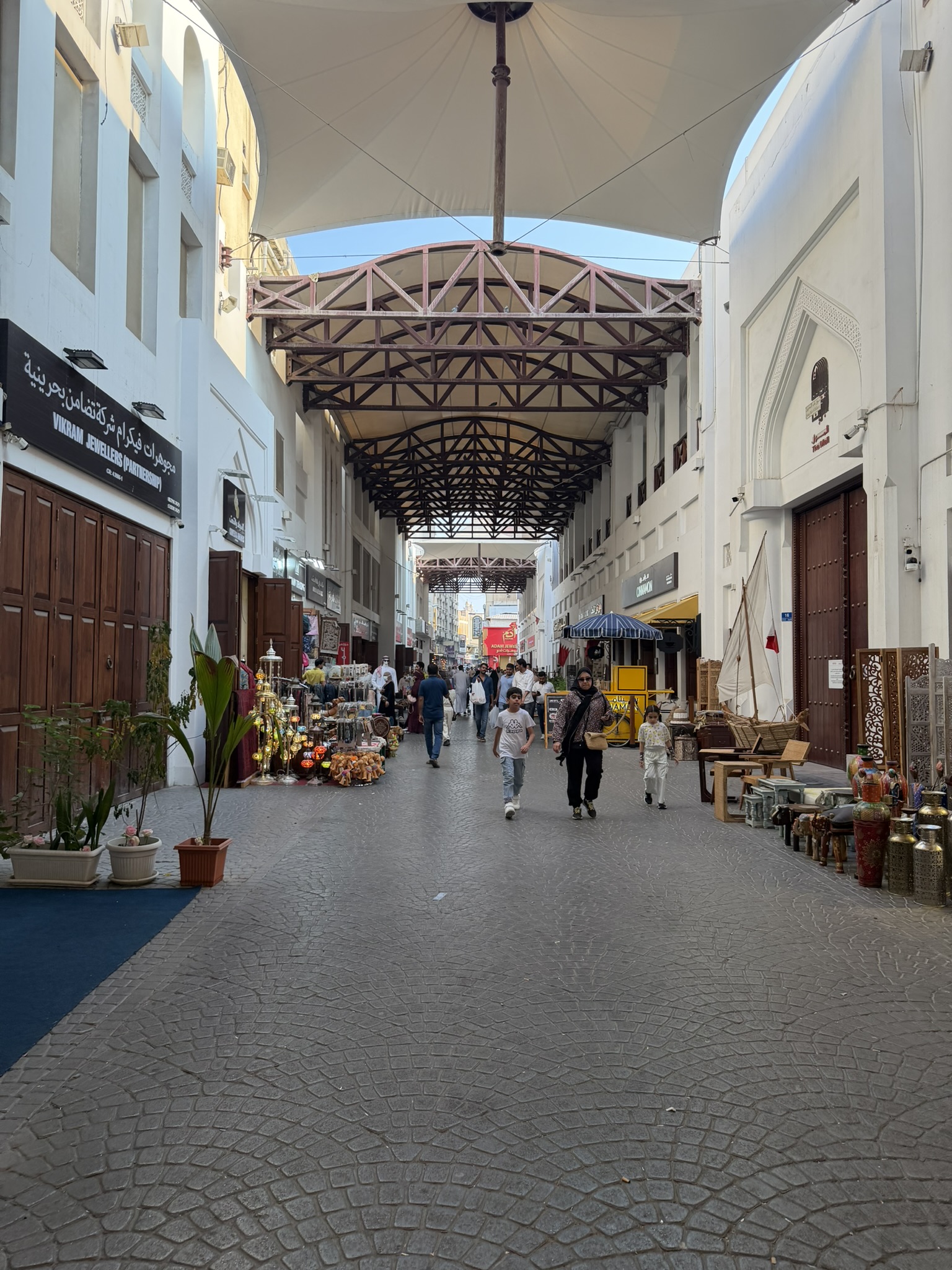 Shoppers walking through the covered walkway of Manama Souk