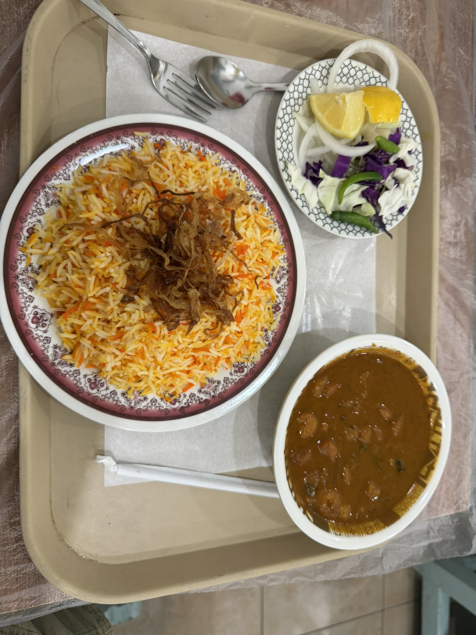 A tray of biryani rice, curry, and salad at Haji's Cafe