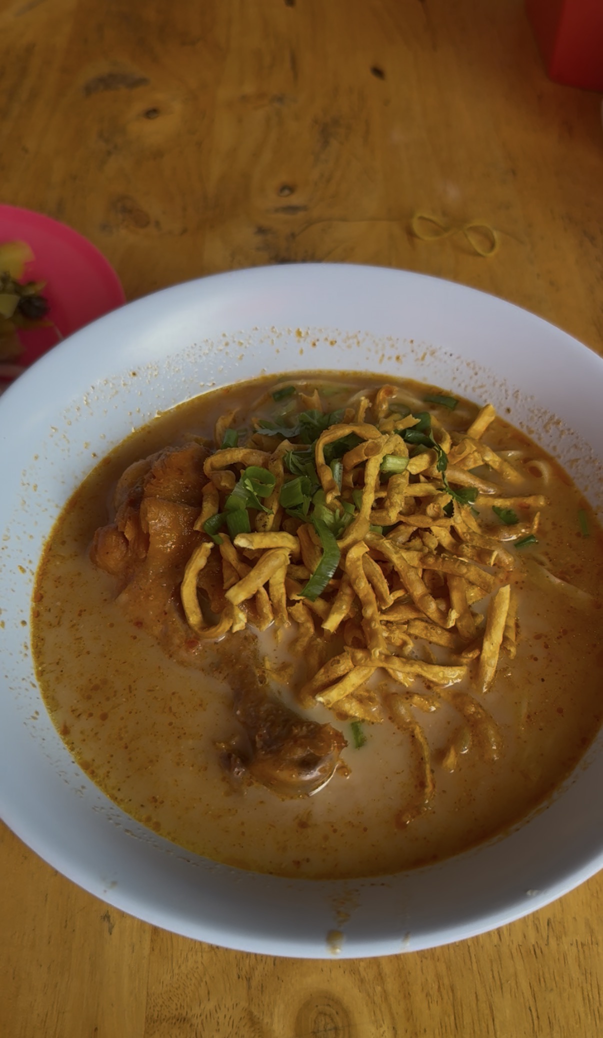 A bowl of Khao Soi with crispy noodles and rich coconut curry broth