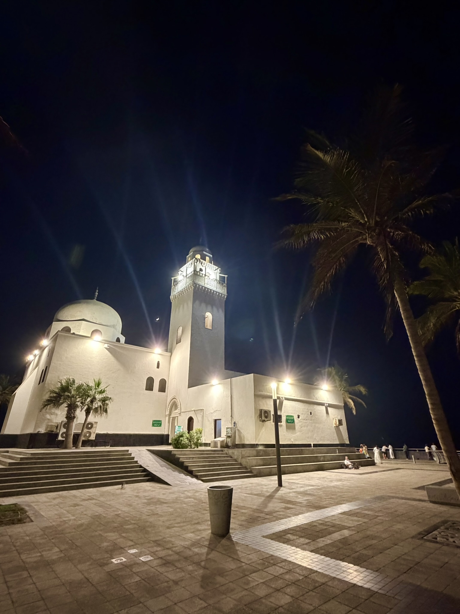 A white mosque with minaret illuminated at night on the Corniche