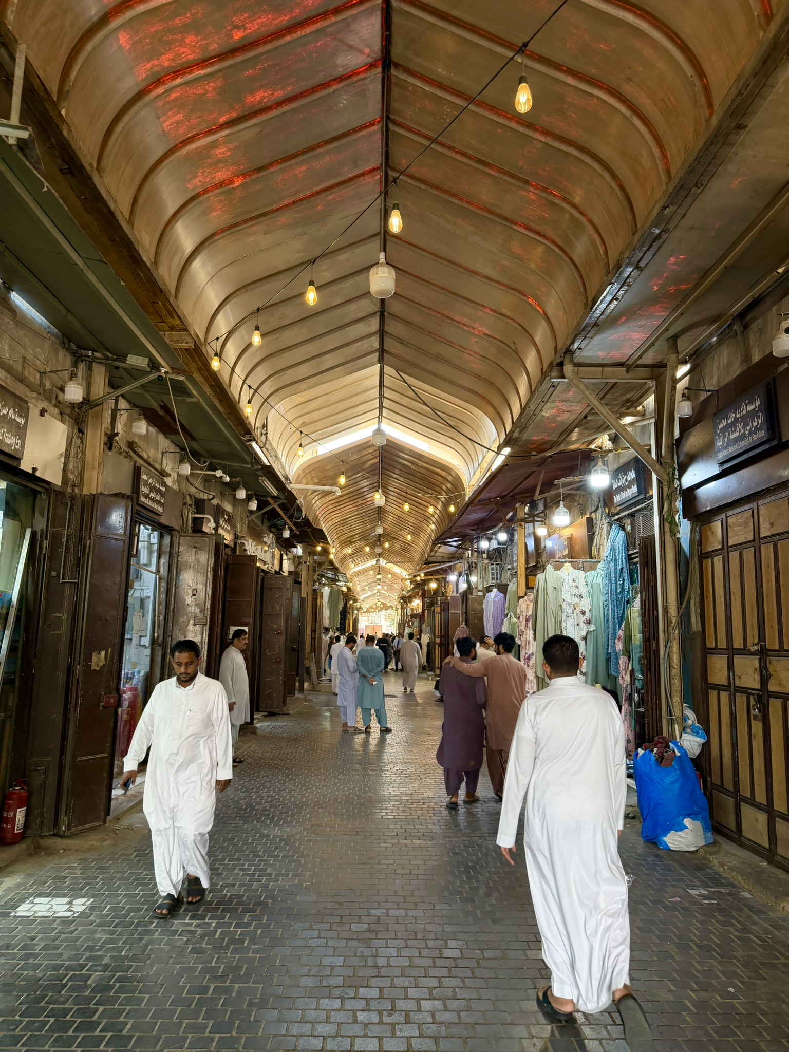 Inside the covered souq with people in traditional white robes