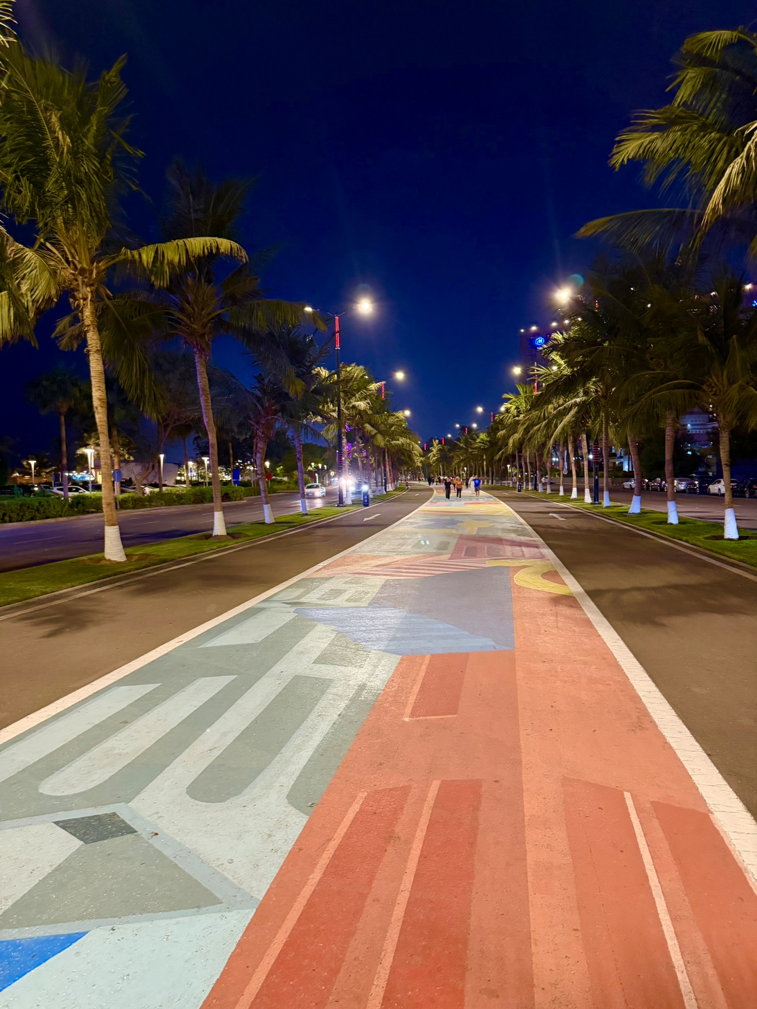 The colorful Jeddah Corniche promenade at night with palm trees