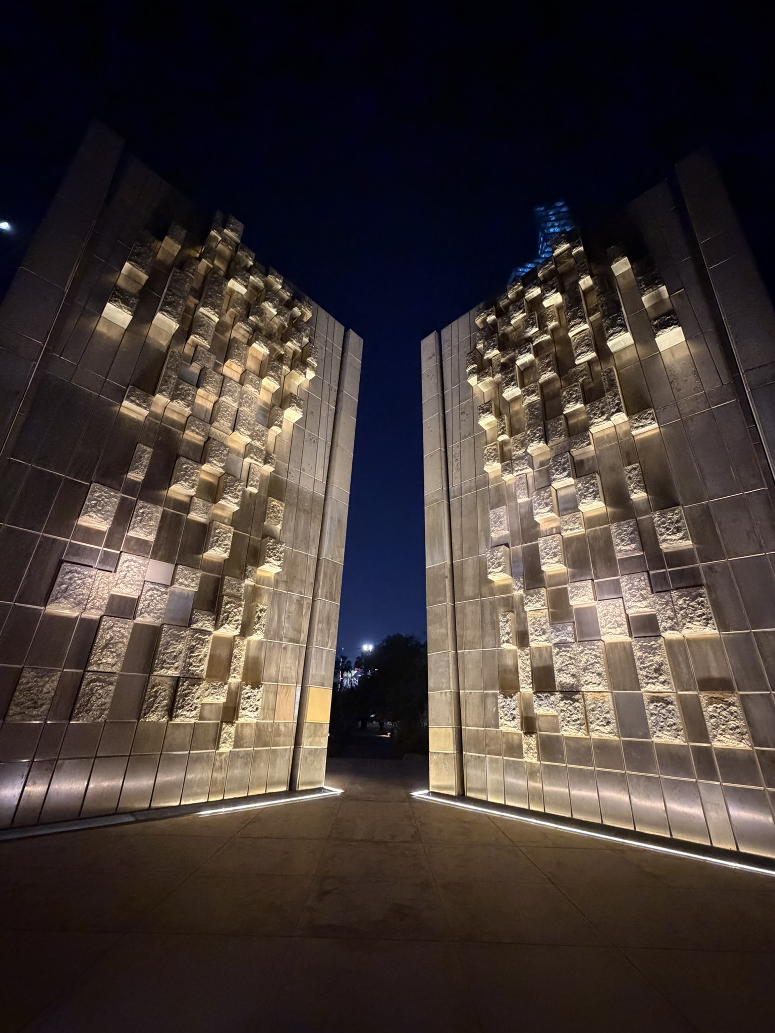 Illuminated textured stone monument walls at Al Shaheed Park at night