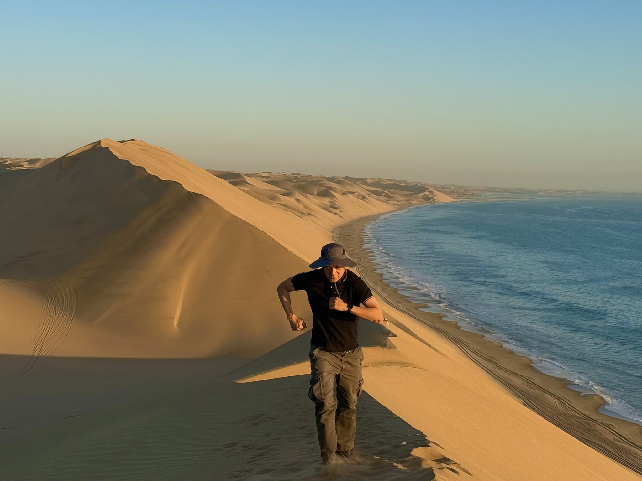 Running down a dune at Sandwich Harbour with ocean in background