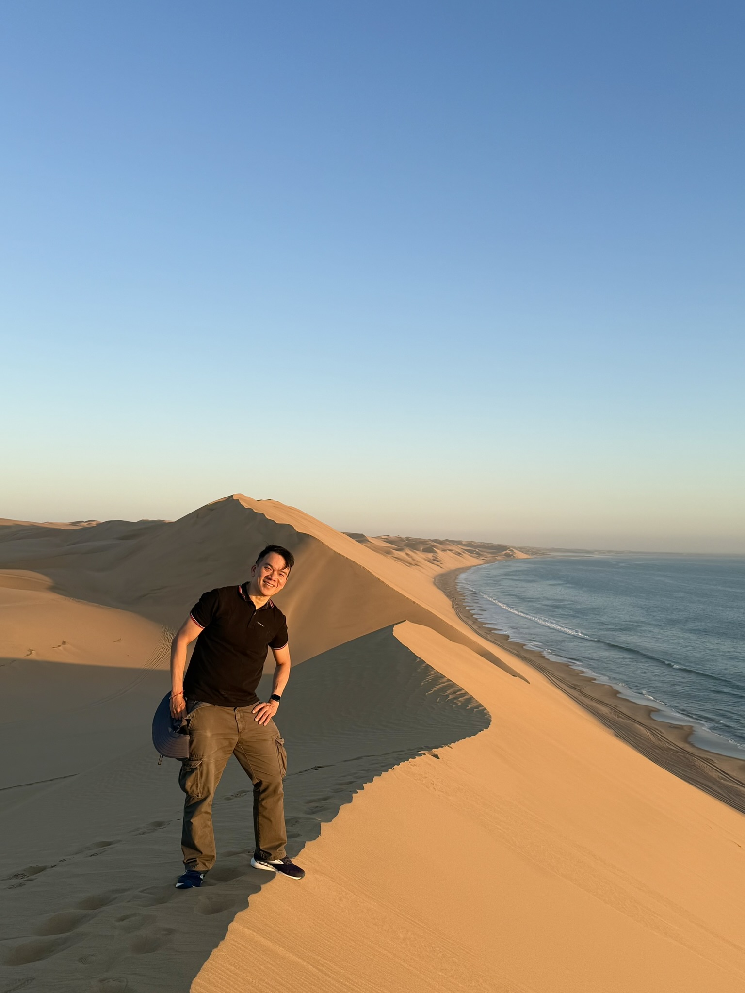 Standing on dune ridge with hat overlooking ocean