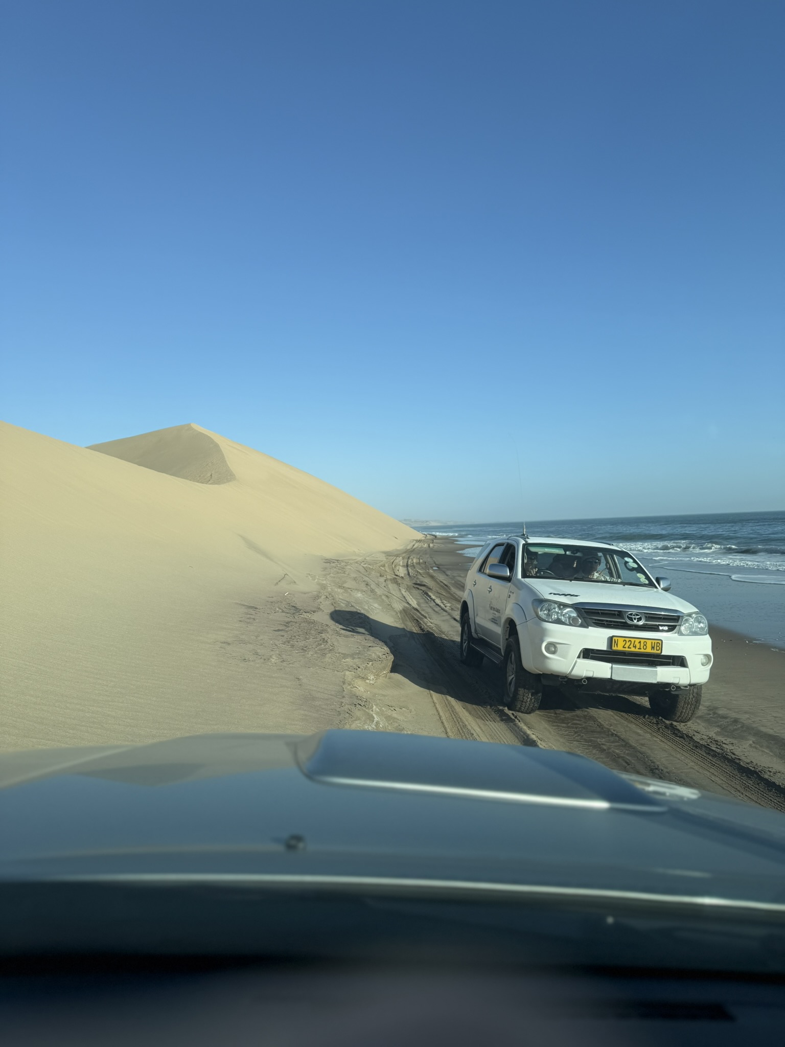 4x4 vehicle driving between dunes and ocean at Sandwich Harbour
