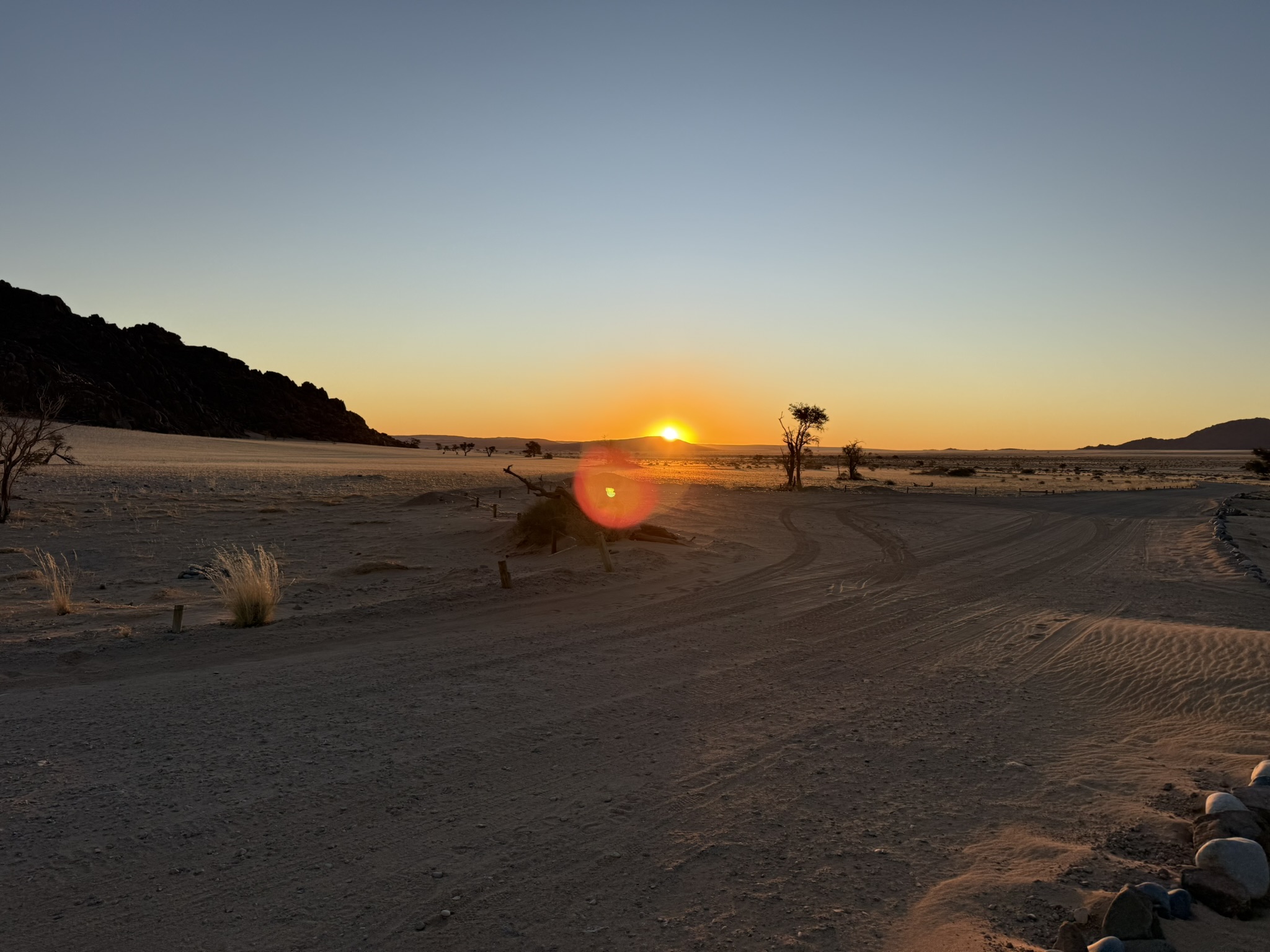 Sunset with sun visible over desert landscape