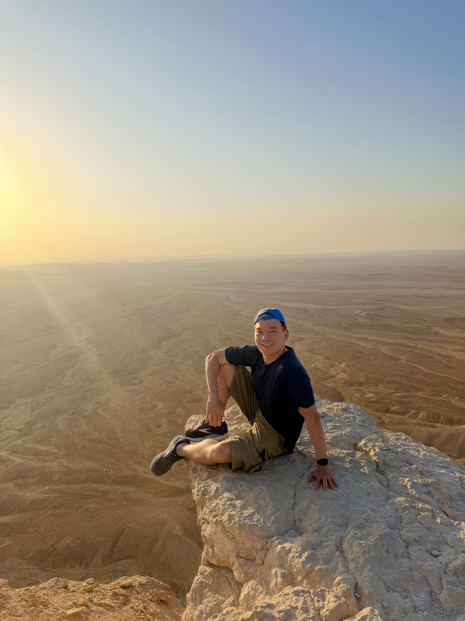 Posing at Edge of the World with vast desert below