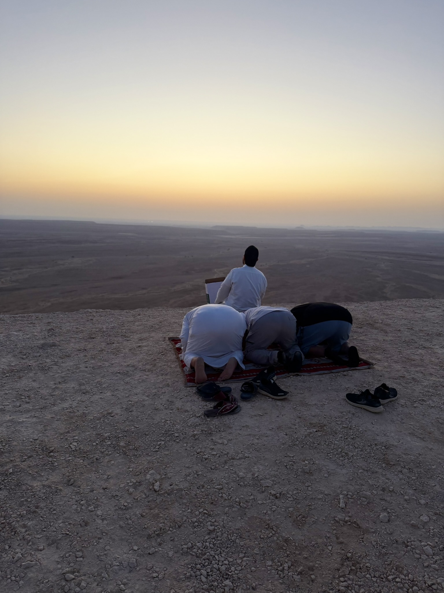 People praying at Edge of the World during sunset